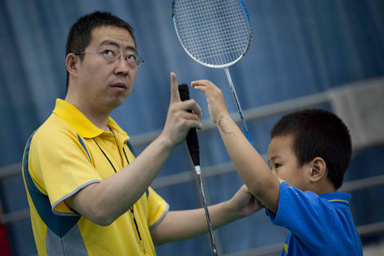 羽毛球教练正在指导小骏挥拍时的动作要领。